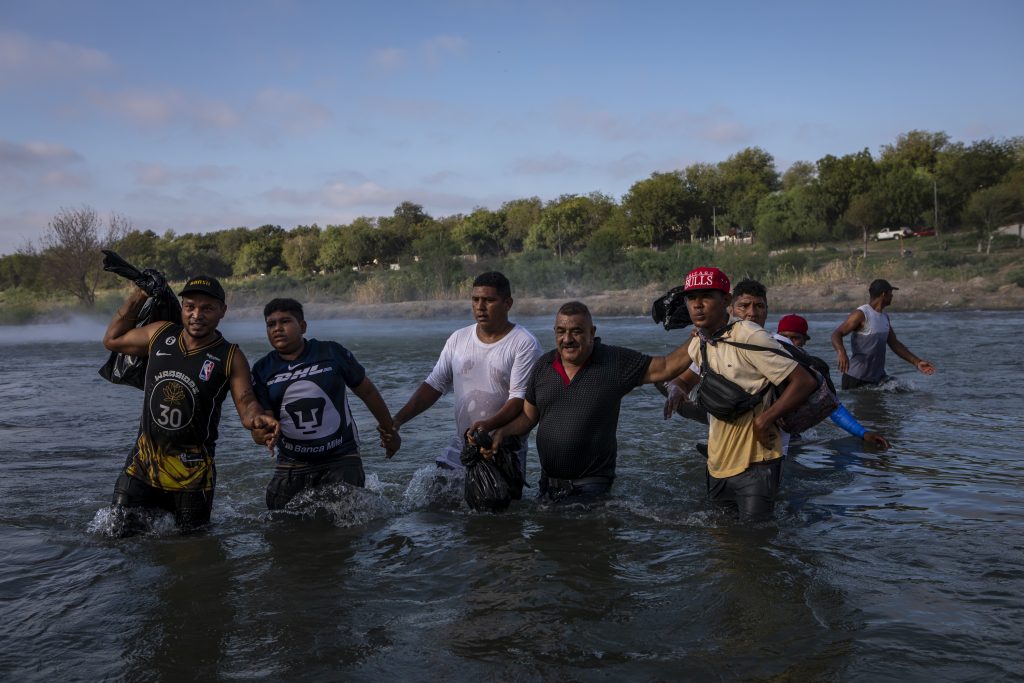 Migrantes cruzan caminando el río Bravo.