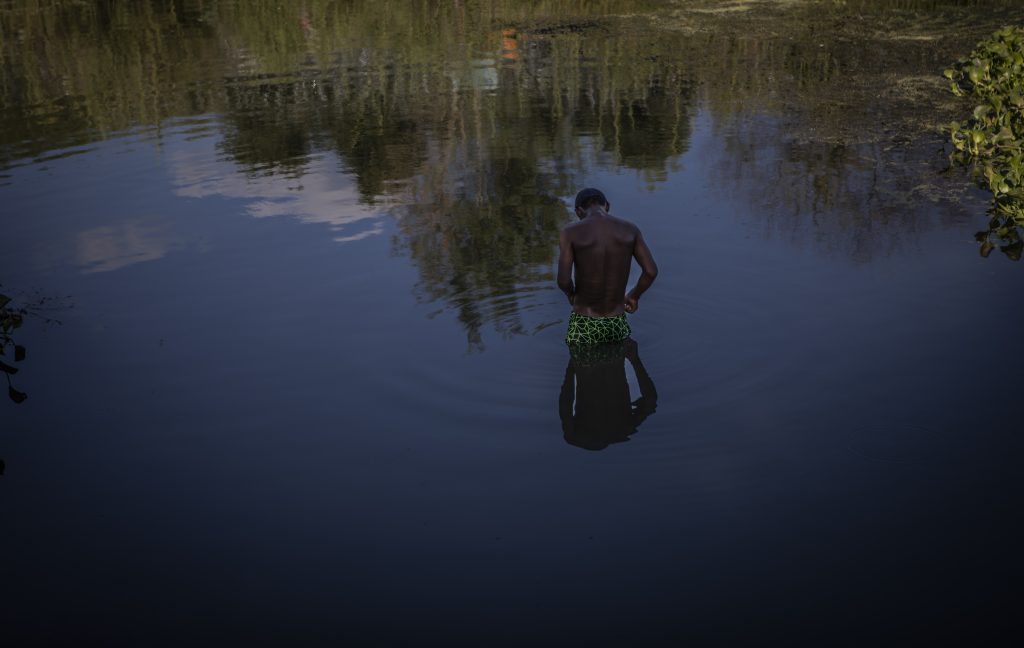 Joven migrante se baña en el río.