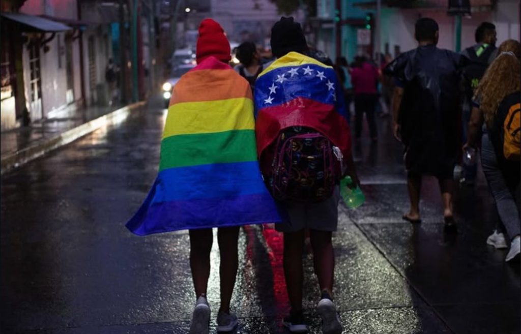 Migrantes envueltos, en las banderas del orgullo LGBTIQ+ y de Venezuela.