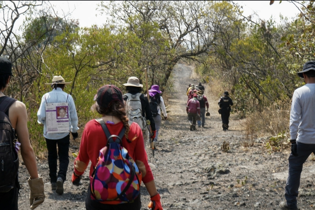 Personas caminando en dirección al polígono de búsqueda por un camino de tierra.