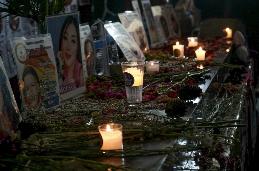 Altar con flores, velas, fotos y fichas de búsqueda de personas desaparecidas.